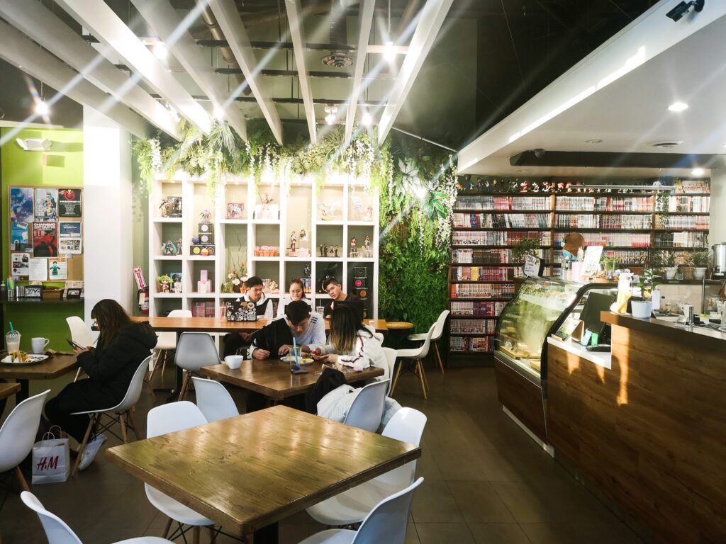 Picture of the interior of Ki Cafe, tables as well as bookshelves filled with anime collection can be seen